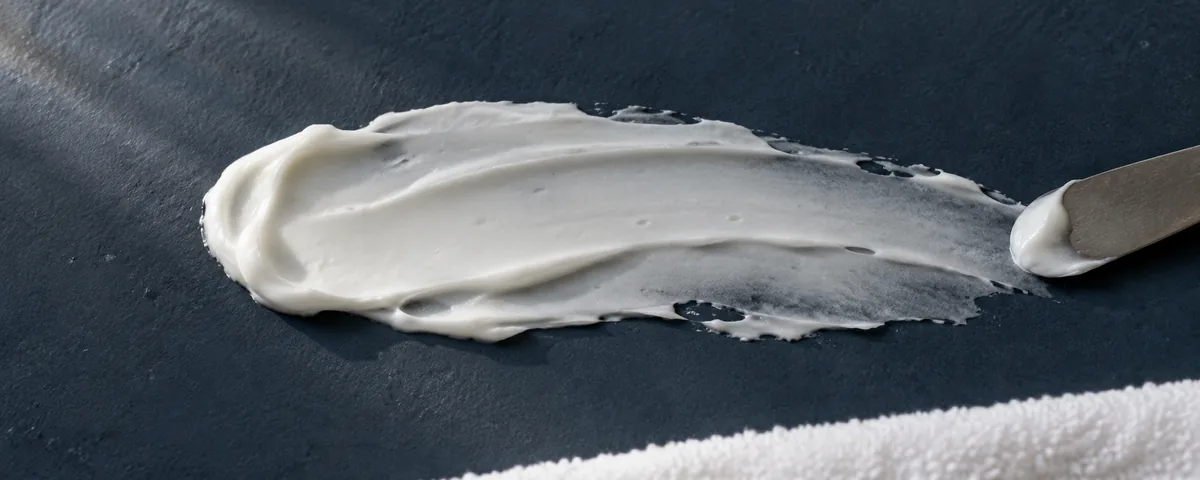 A textured white moisturizer smear on a navy ceramic surface