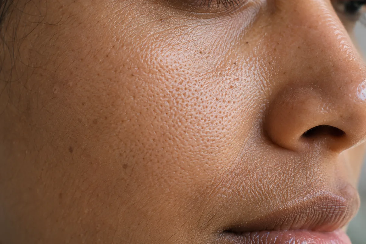 Close view of natural pores and fine hairs on an adult cheek