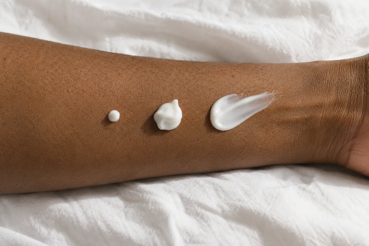 Three different amounts of cosmetic cream on a forearm
